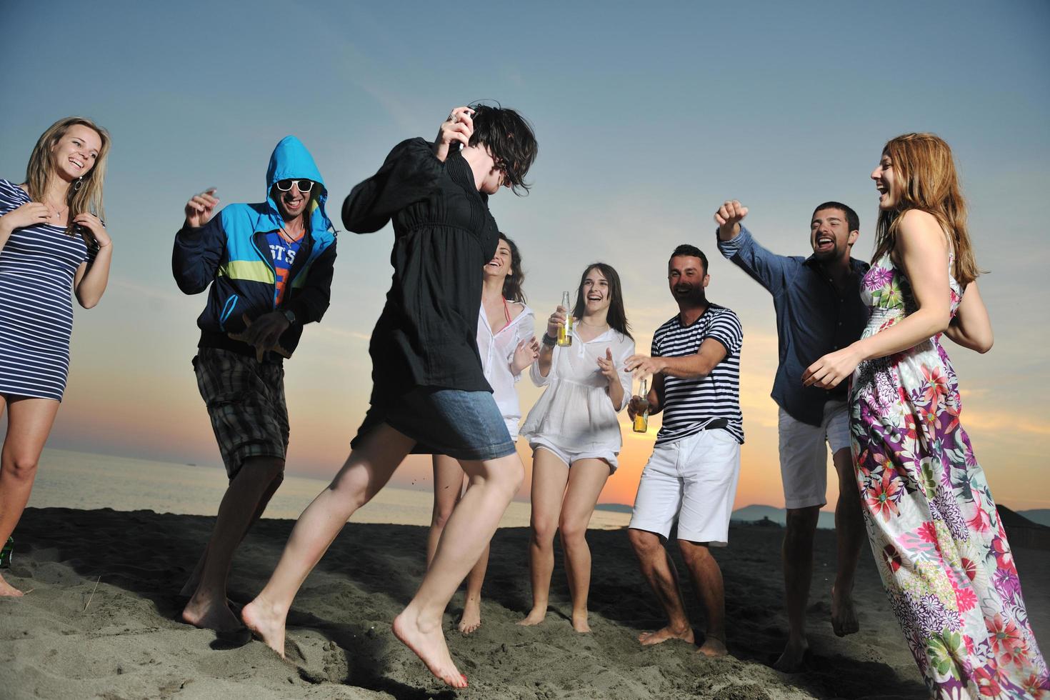 gruppo di giovane persone godere estate festa a il spiaggia foto