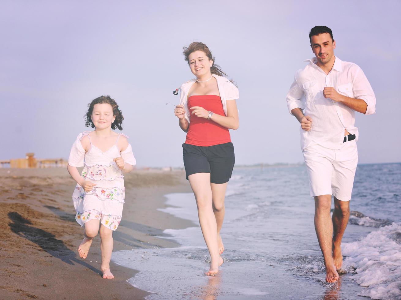 contento giovane famiglia avere divertimento su spiaggia foto