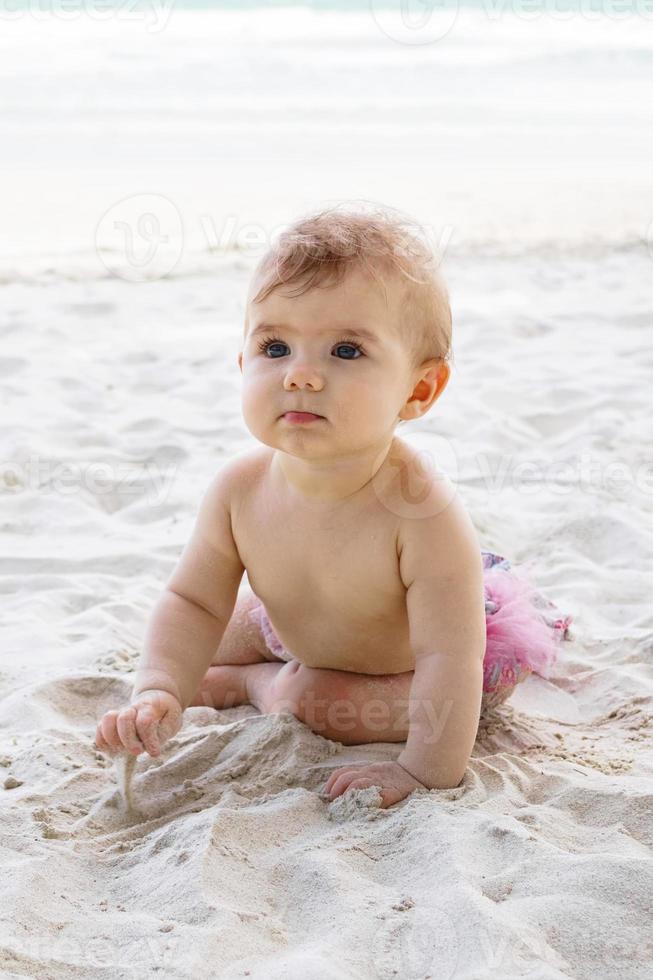 Candido ritratto di adorabile poco bambino ragazza su sabbia a spiaggia su sfondo di mare. sensoriale sviluppo per bambini all'aperto. foto