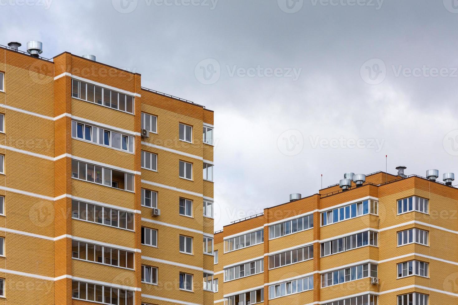 nuovo alto salire giallo-arancione mattone appartamento edifici a nuvoloso giorno luce, avvicinamento teleobiettivo Visualizza foto