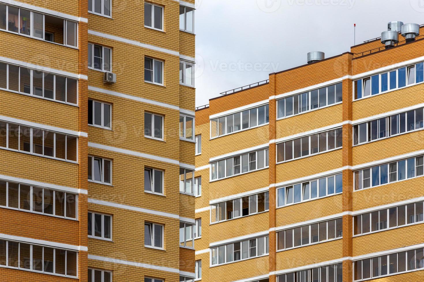 nuovo alto salire giallo-arancione mattone appartamento edifici a nuvoloso giorno luce, avvicinamento teleobiettivo Visualizza foto