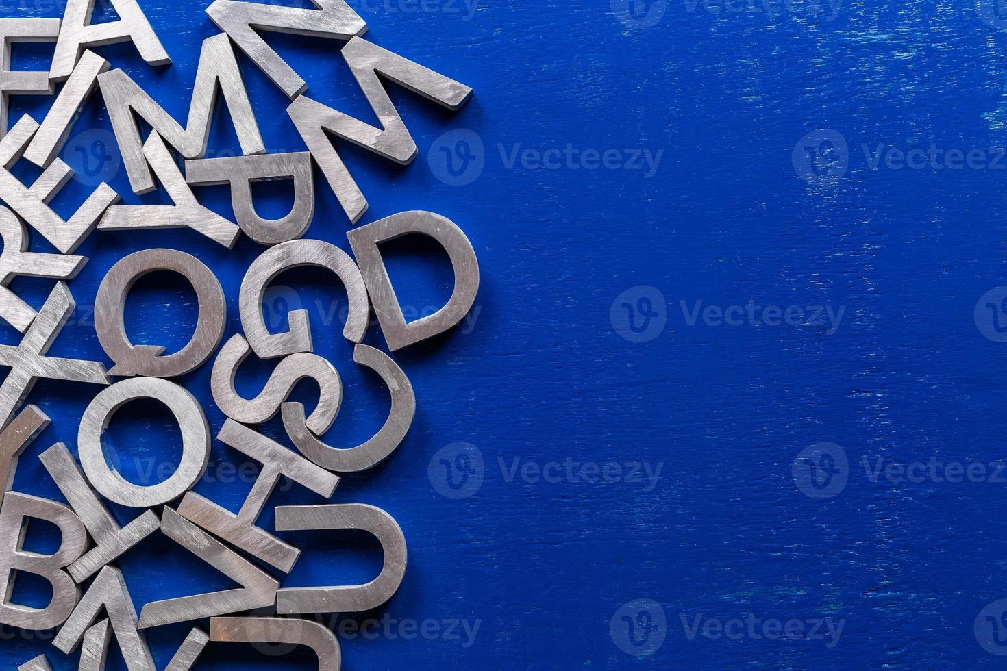 piatto modello di argento metallo alfabeto personaggi su blu dipinto tavola sfondo con copyspace. foto