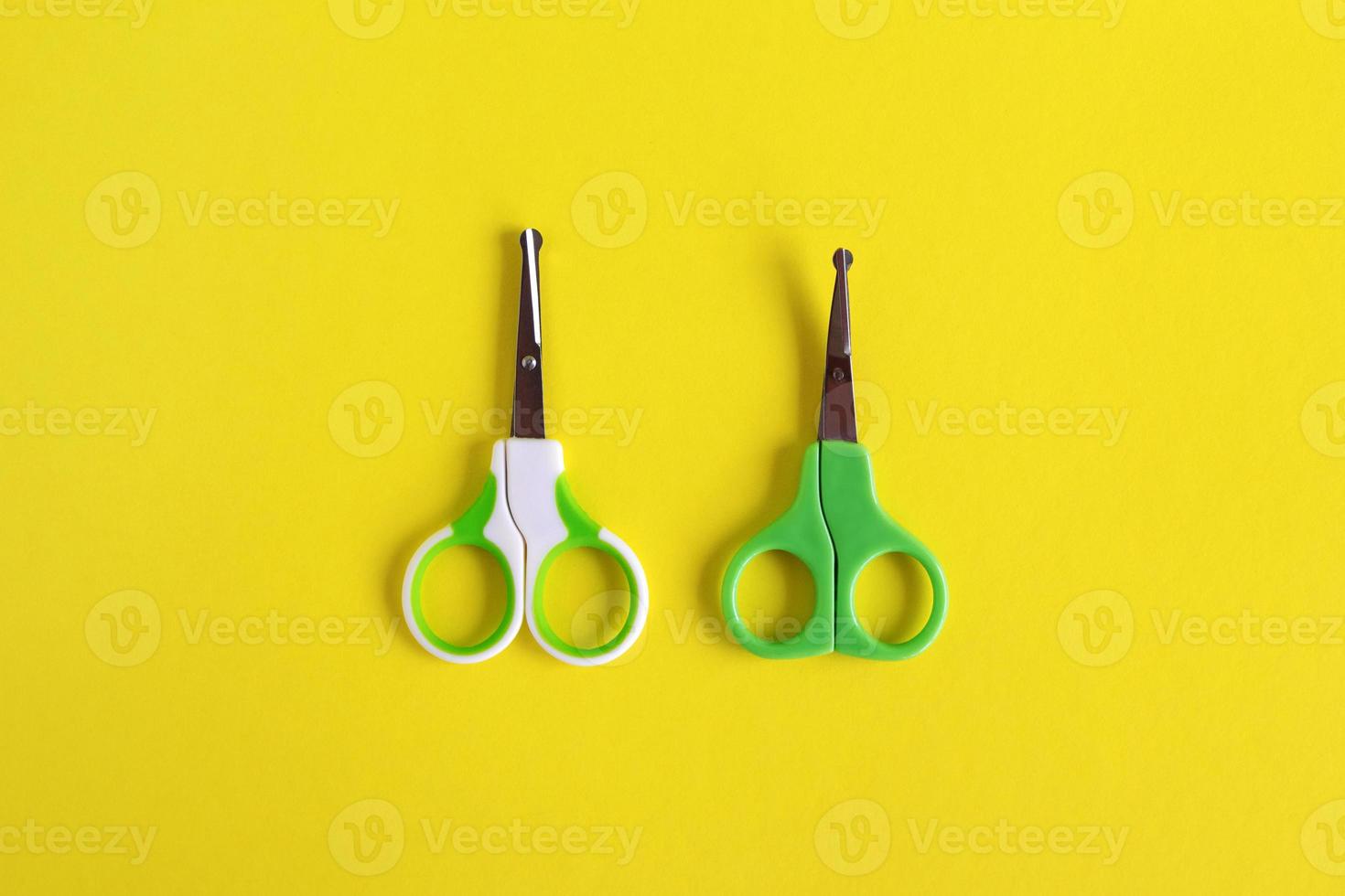 Due bambino verde forbici su giallo sfondo, piatto posare con copia spazio. bambino cura concetto. foto
