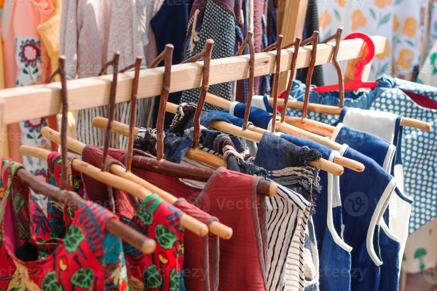 Abiti cremagliere con cotone colorato etnico vestiti su di legno grucce. vetrina con Abiti su Locale strada mercato. foto