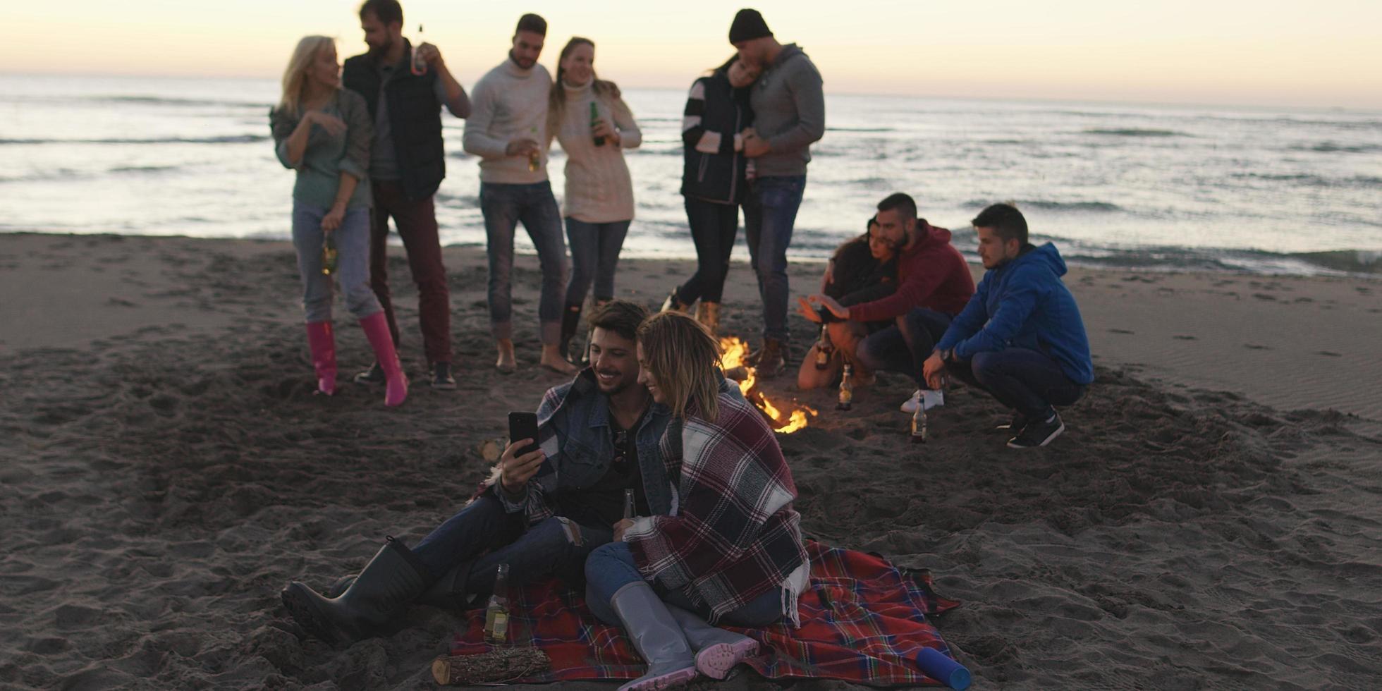 amici avendo divertimento a spiaggia su autunno giorno foto