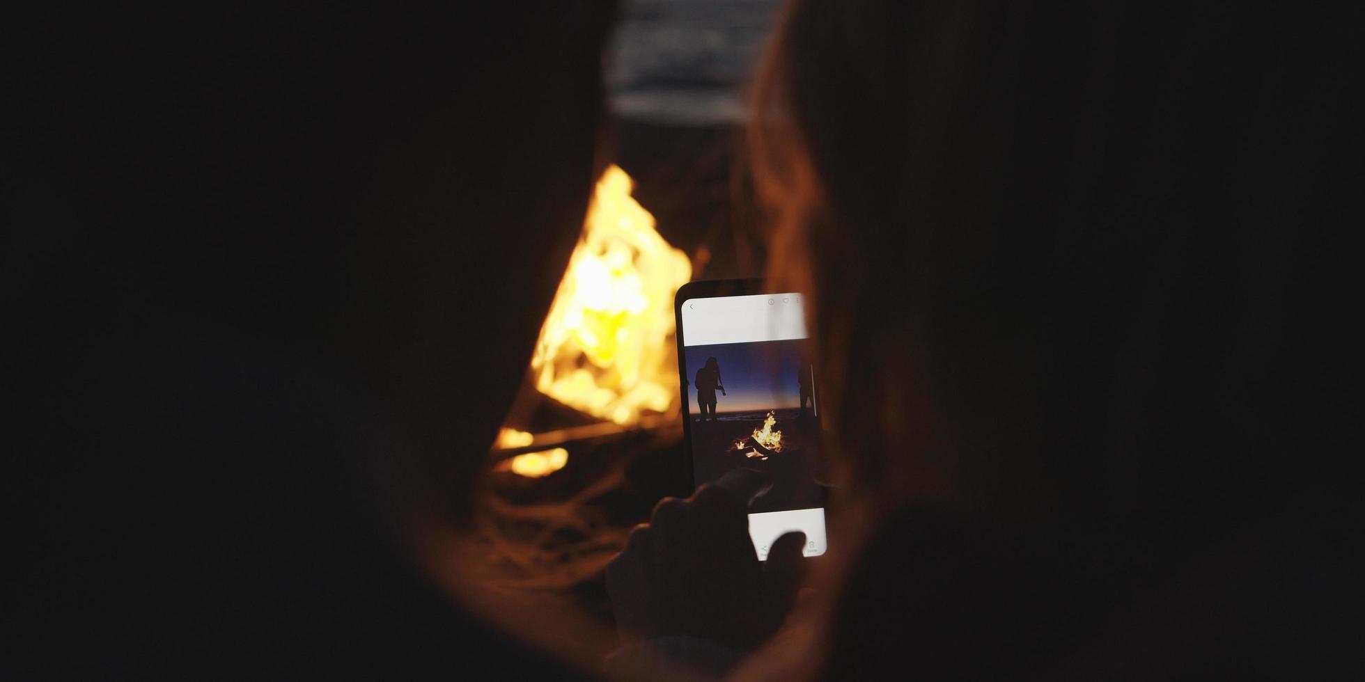 coppia assunzione fotografie accanto fuoco di bivacco su spiaggia