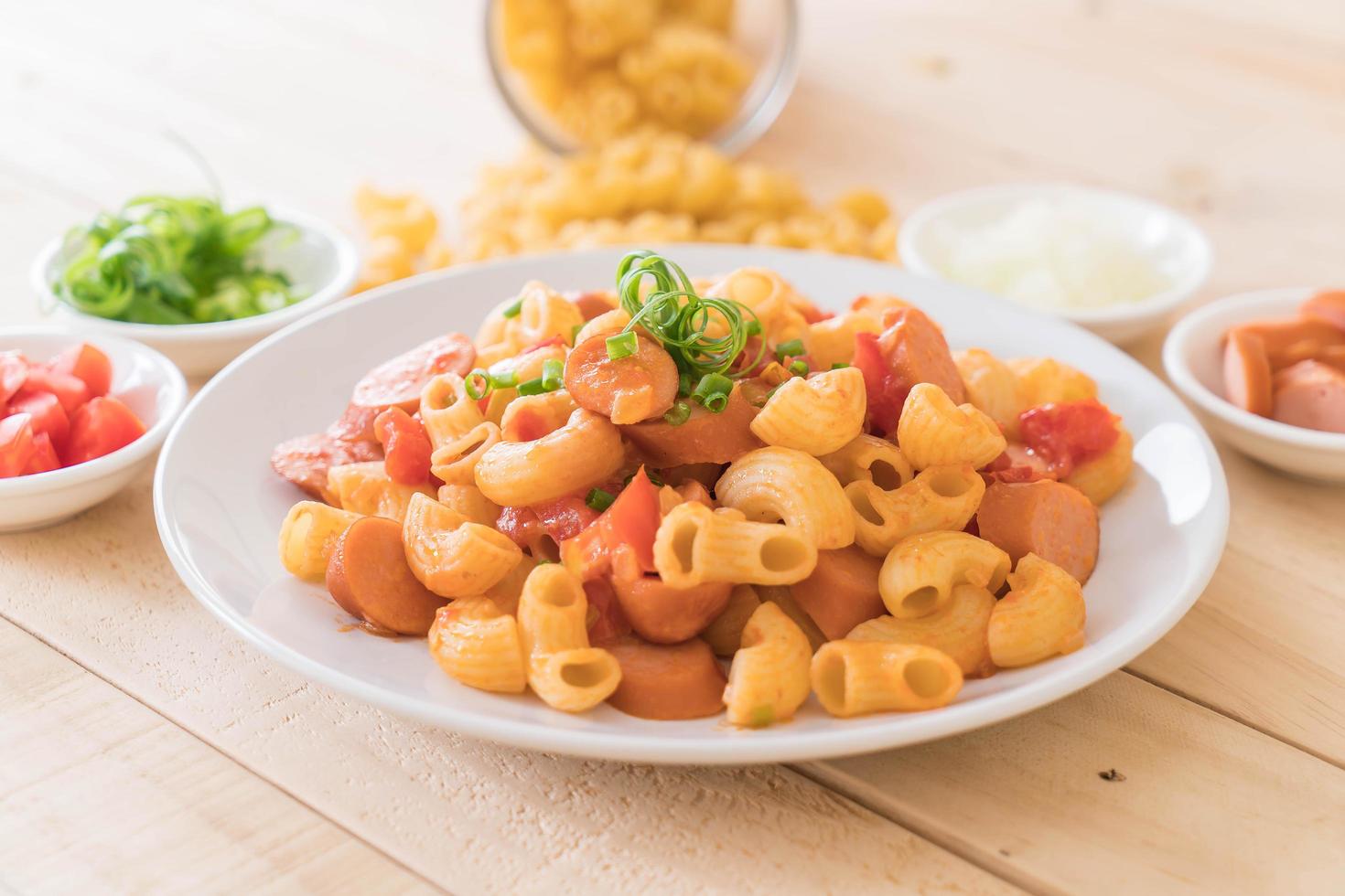 piatto di salsiccia e maccheroni sulla tavola di legno foto