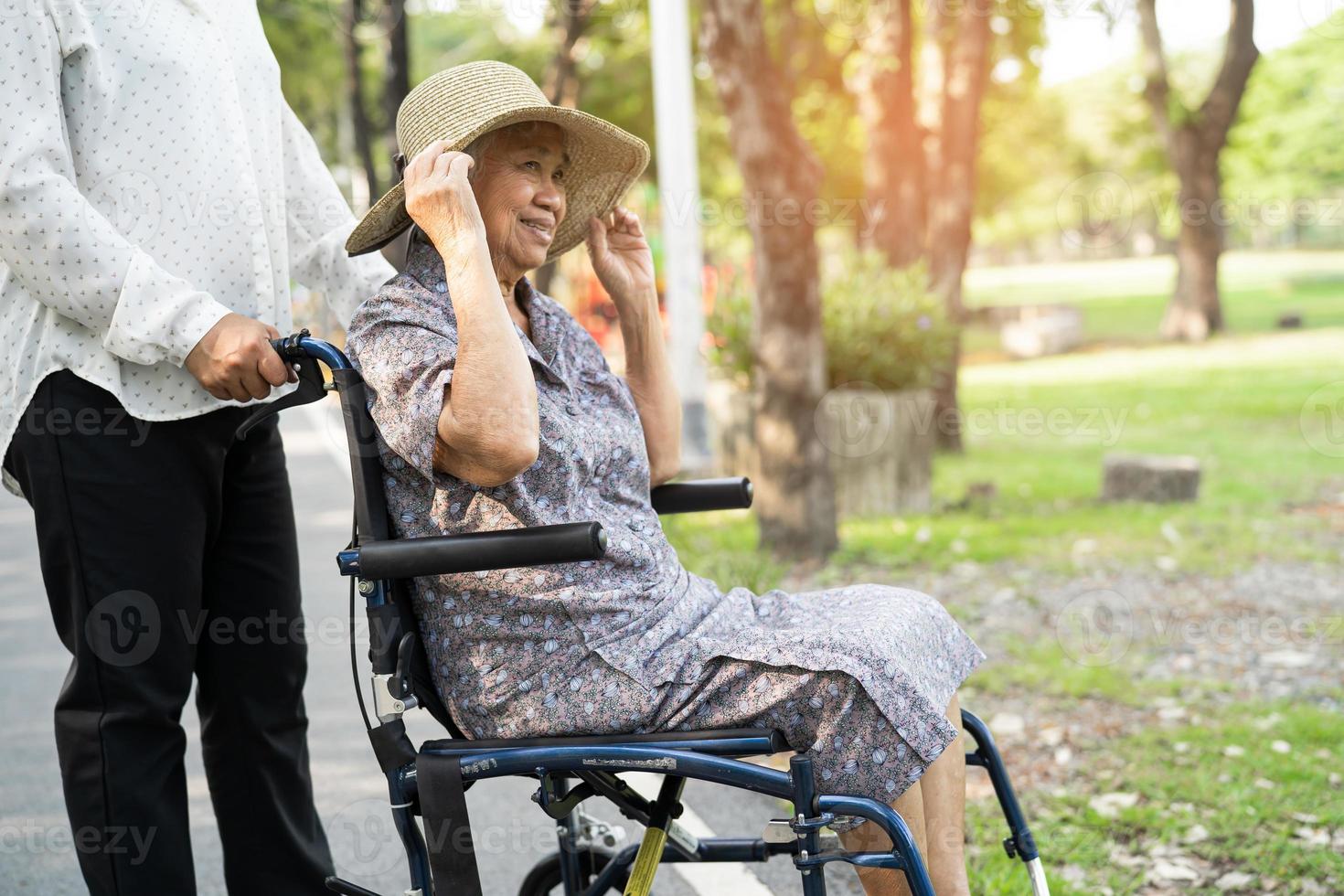badante aiuto e cura asiatico anziano o anziano donna paziente seduta e felice sulla sedia a rotelle nel parco, sano concetto medico forte. foto