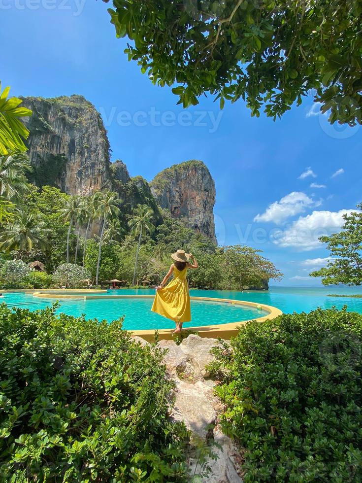 turista donna in abito giallo e cappello che viaggia sulla spiaggia di Railay, Krabi, Thailandia. concetto di vacanza, viaggio, estate, voglia di viaggiare e vacanza foto