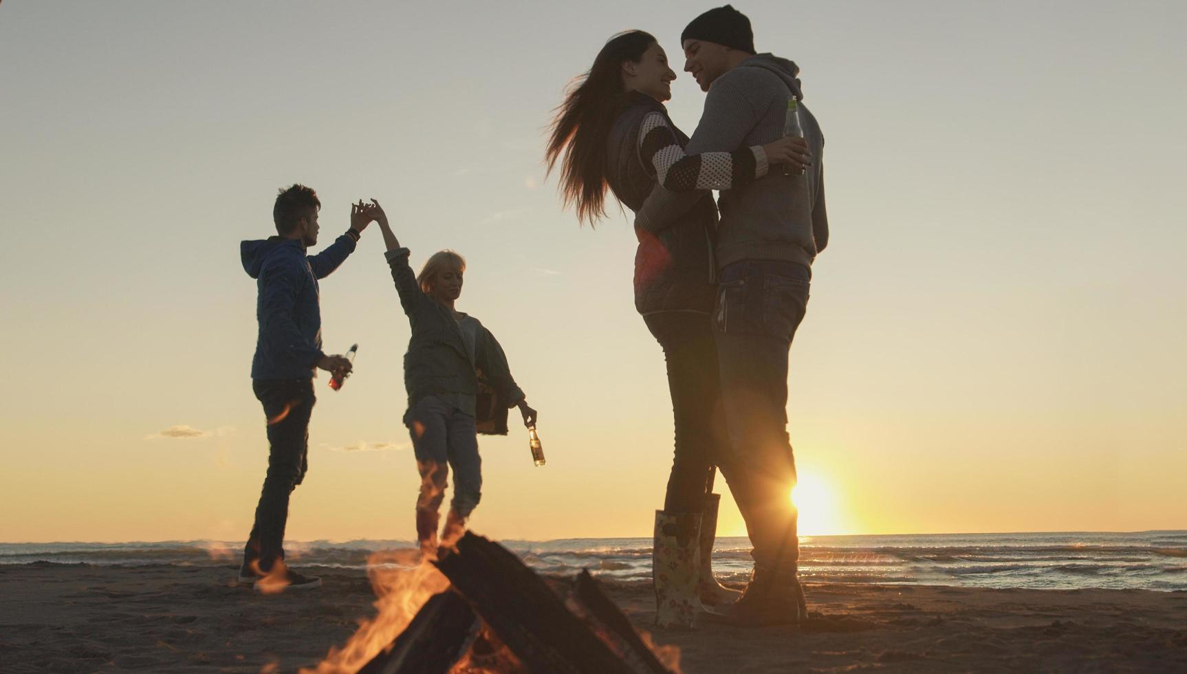 amici avendo divertimento a spiaggia su autunno giorno foto