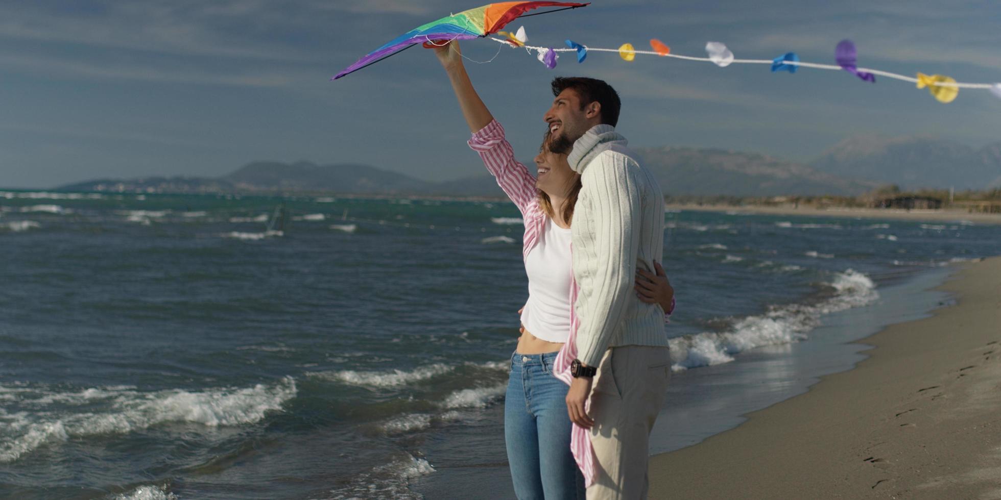 contento coppia avendo divertimento con aquilone su spiaggia foto