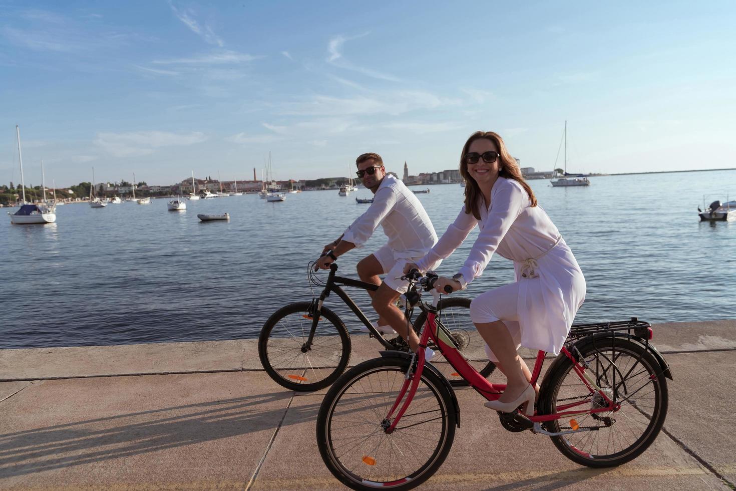 anziano coppia godendo un' bellissimo mattina insieme equitazione un' bicicletta di il mare. selettivo messa a fuoco foto