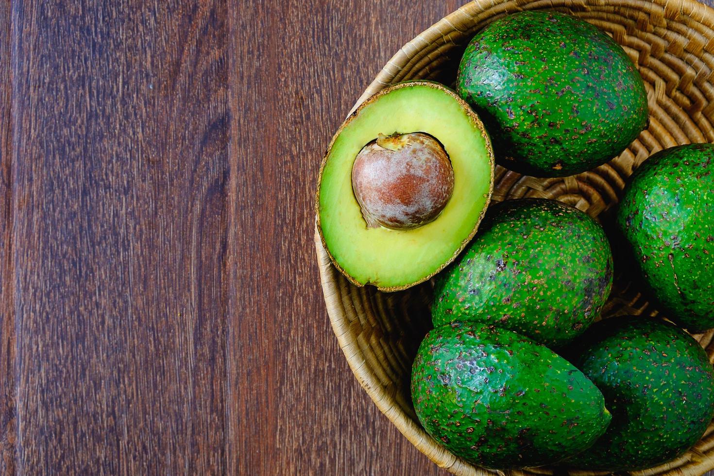 frutto di avocado in un cesto sul tavolo di legno foto