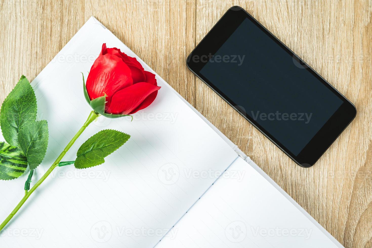 rosso Rose su vuoto taccuino con smartphone San Valentino concetto foto