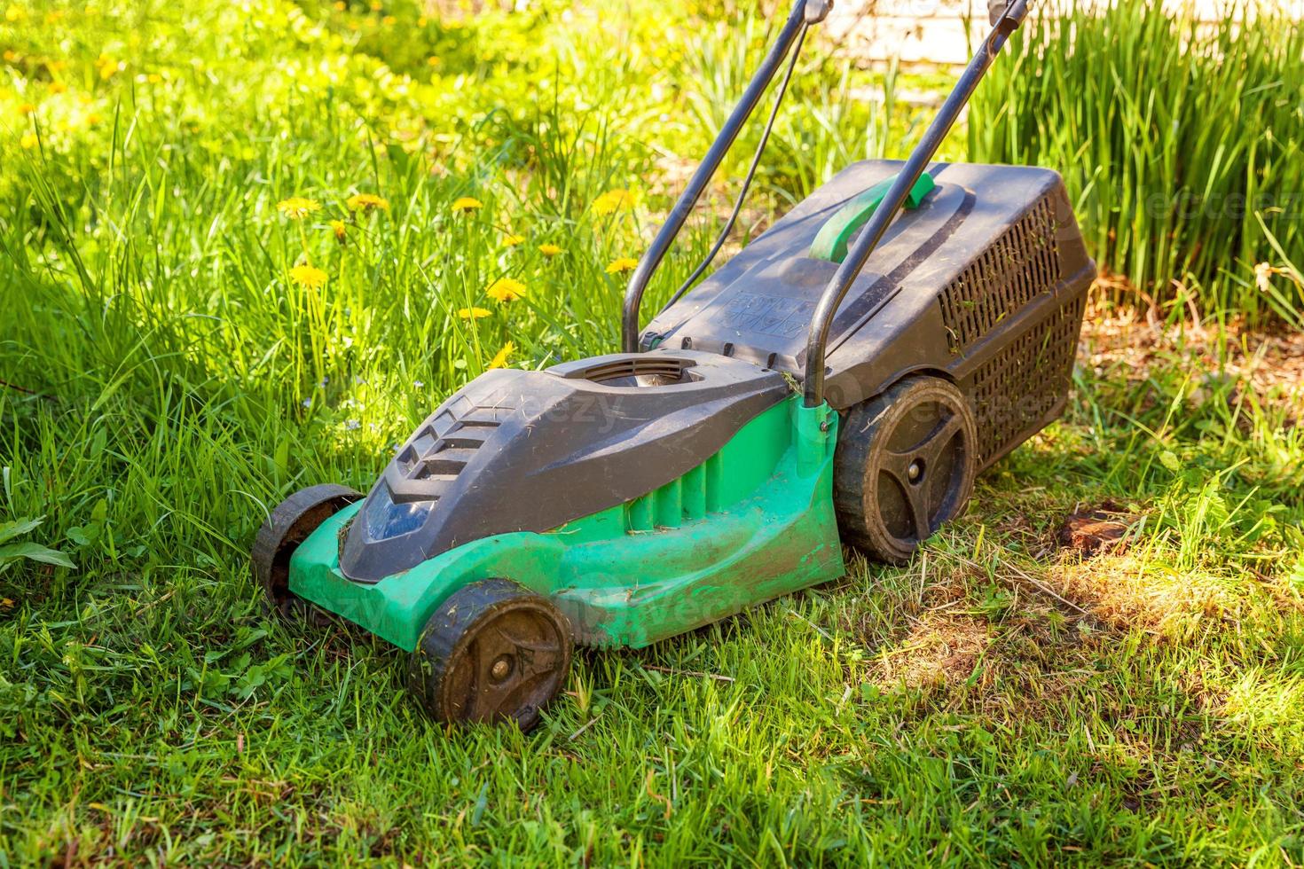 prato falciatore taglio verde erba nel Giardino dietro la casa nel soleggiato giorno. giardinaggio nazione stile di vita sfondo. bellissimo Visualizza su fresco verde erba prato nel luce del sole, giardino paesaggio nel primavera o estate stagione. foto