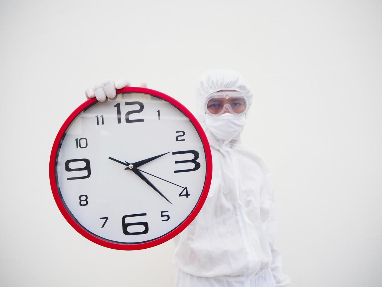 ritratto di medico o scienziato nel ppe suite uniforme Tenere rosso allarme orologio e guardare a il telecamera nel vario gesti. covid-19 concetto isolato bianca sfondo foto