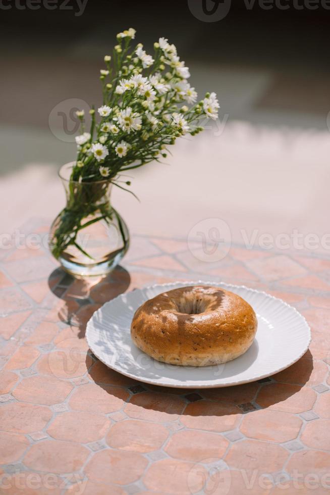 ciambella su bianca piatto su tavolo sfondo sotto naturale luce del sole foto