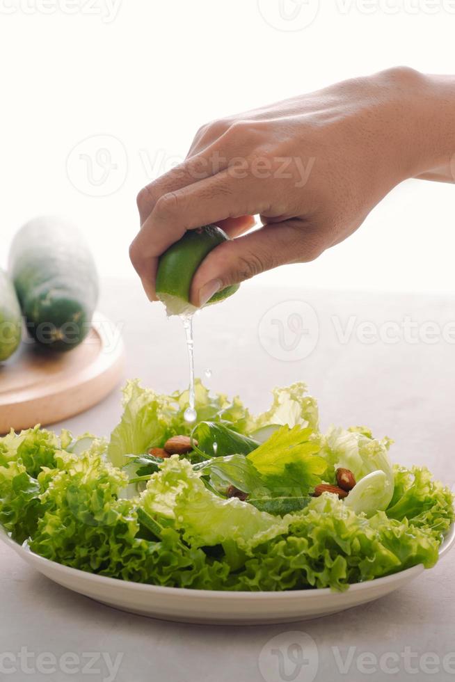 verde vegano prima colazione pasto nel ciotola con lattuga, cetriolo, lime e mandorla. ragazza Tenere piatto con mani visibile, superiore Visualizza. pulito mangiare, dieta, vegano cibo concetto foto