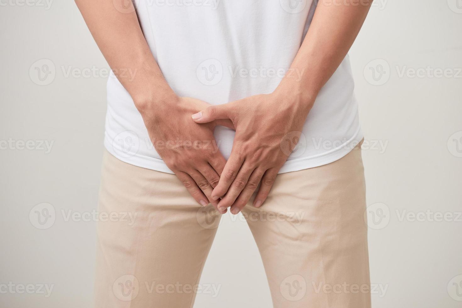 uomo mani Tenere su mezzo forcella di i pantaloni con dolore azione isolato su bianca sfondo. foto