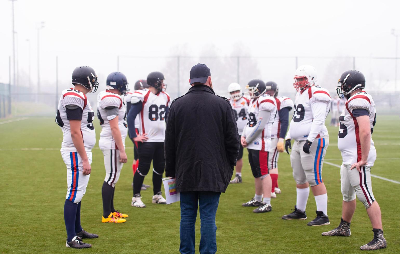 americano calcio Giocatori discutere strategia con allenatore foto