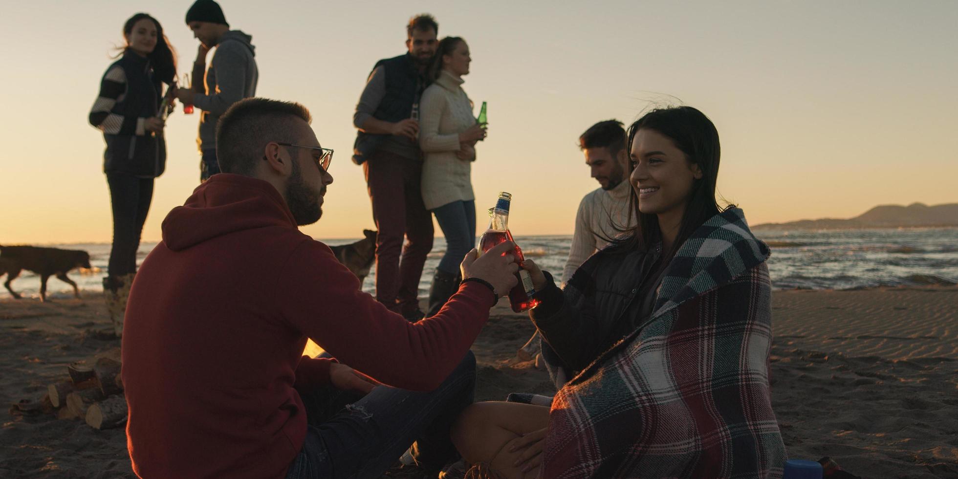 amici avendo divertimento a spiaggia su autunno giorno foto