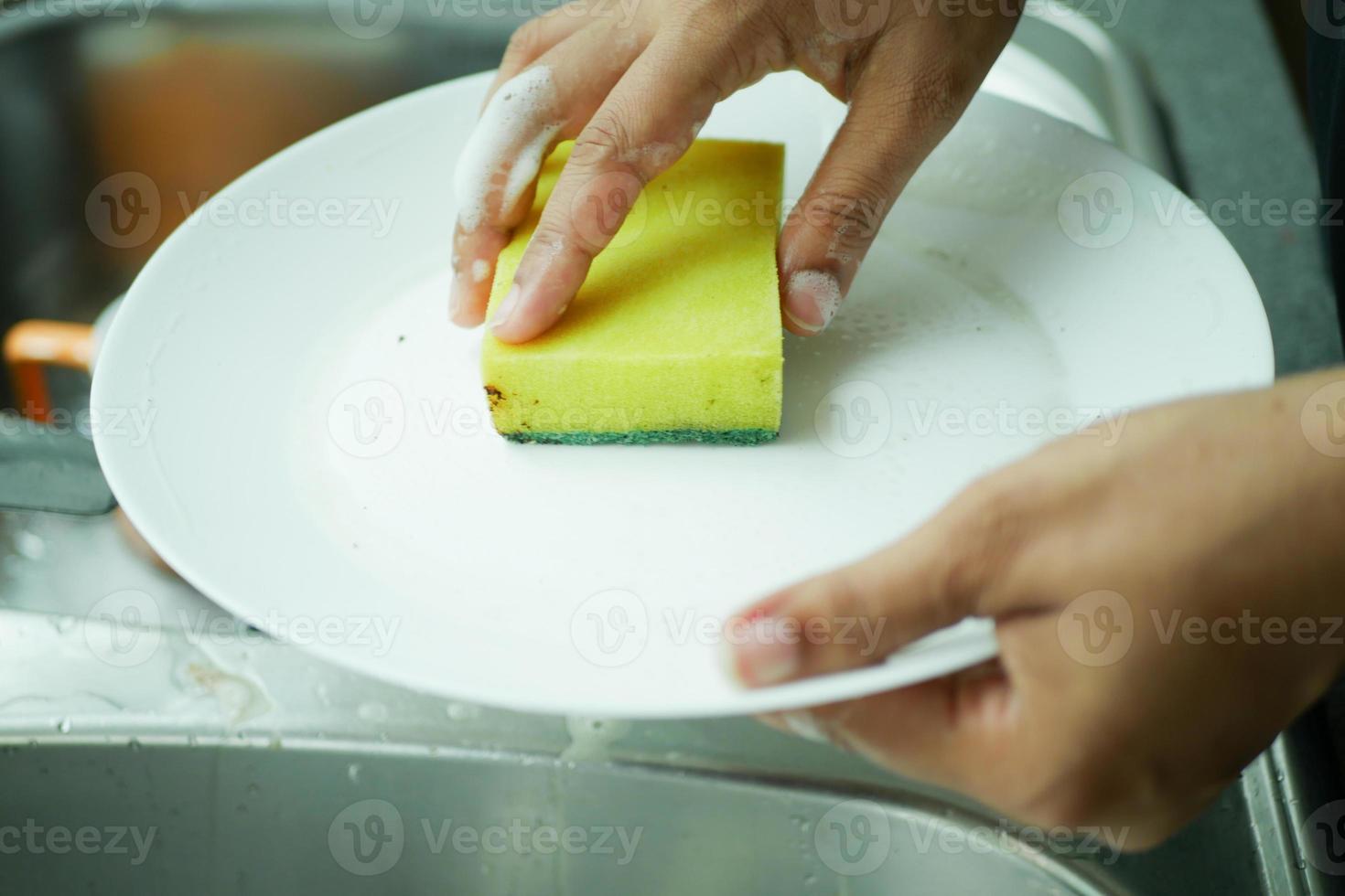donne mano pulizia piatto con un' spugna foto