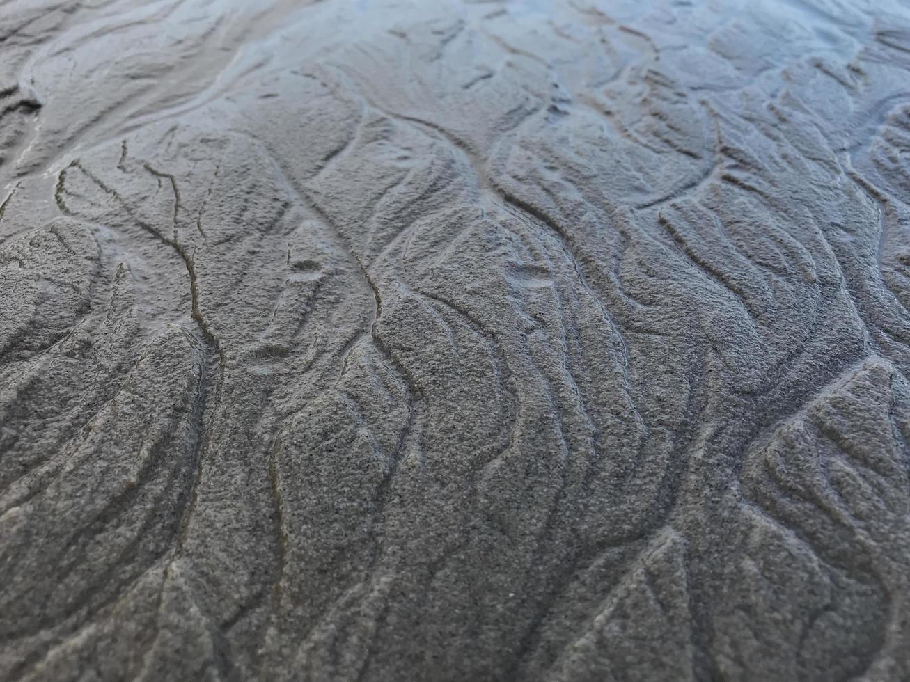 Questo è un' immagine di un' sfondo di sabbia su il spiaggia quello ha appena stato lavato lontano di il onde foto