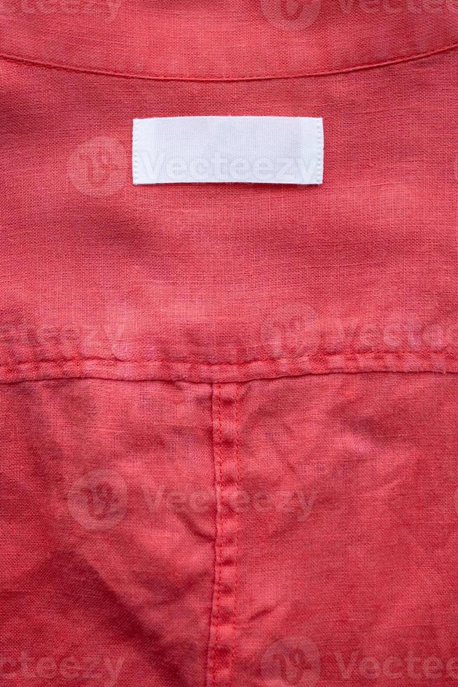 bianca vuoto capi di abbigliamento etichetta etichetta su rosso biancheria camicia tessuto struttura sfondo foto