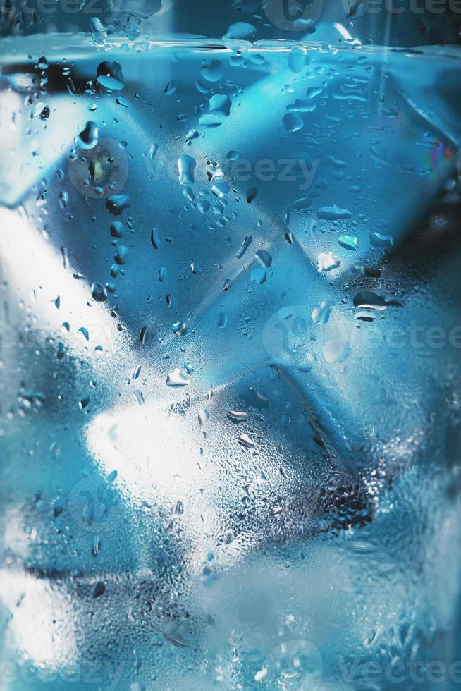 bicchiere con acqua e ghiaccio cubi su un' blu sfondo foto