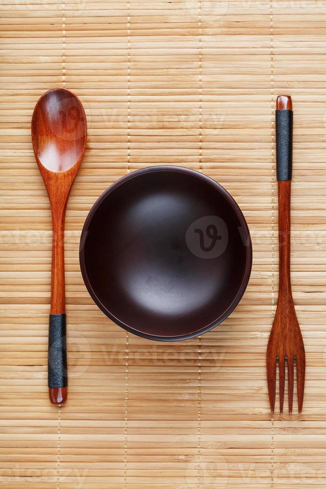 utensili fatto di Di legno, ciotola e cucchiai su un' taglio tavola su un' bianca sfondo foto