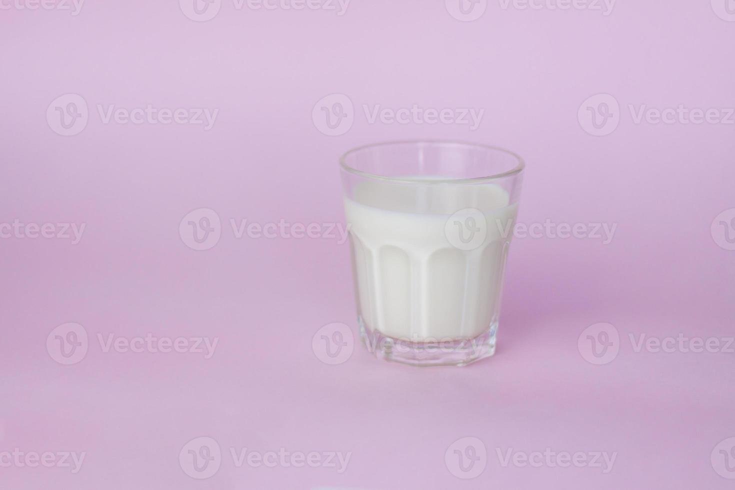 un' bicchiere di bianca latte, evidenziato su un' rosa sfondo, avvicinamento. foto