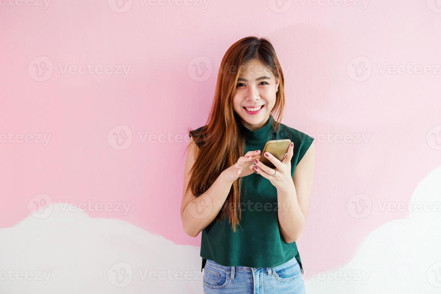 ritratto di giovane donna, guardare a telecamera con affascinante Sorridi mentre utilizzando un' inteligente Telefono, davanti Visualizza foto