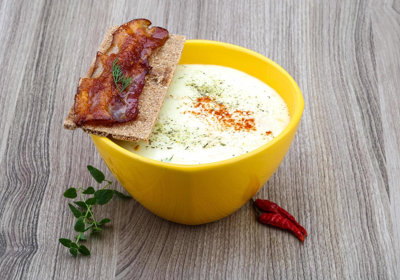 zuppa di formaggio in una ciotola su fondo di legno foto