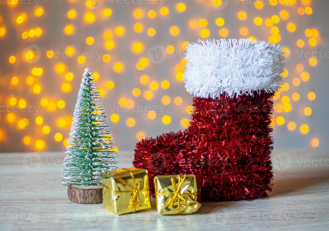 rosso Babbo Natale stivale su legna tavolo con bokeh leggero sfondo foto