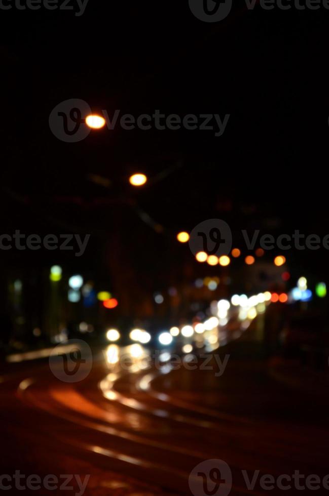 sfocato notte scena di traffico su il carreggiata. sfocato Immagine di macchine in viaggio con luminoso fari. bokeh arte foto