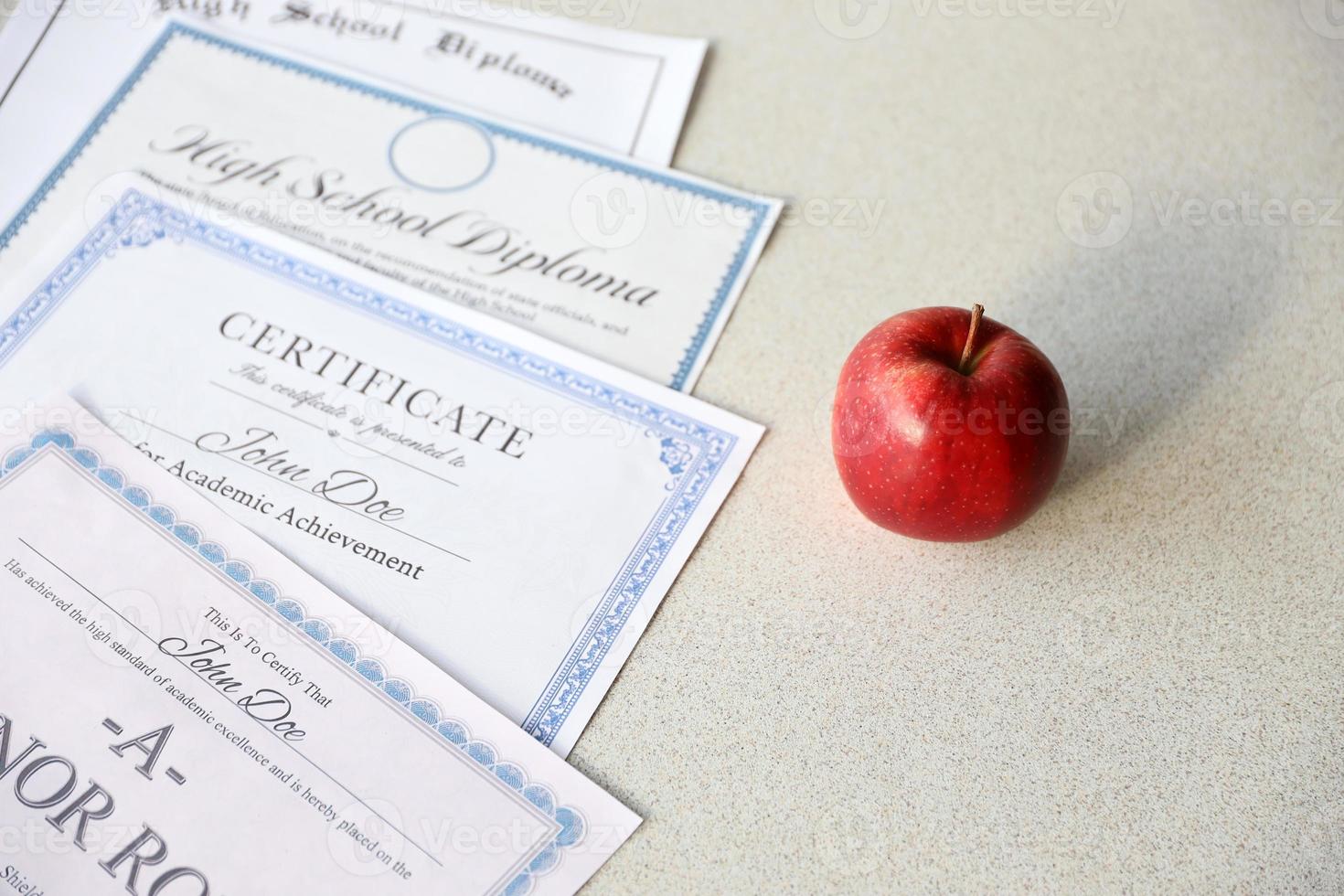 un' onore rotolo riconoscimento, certificato di realizzazione e alto scuola diploma bugie su tavolo con rosso Mela. formazione scolastica documenti foto