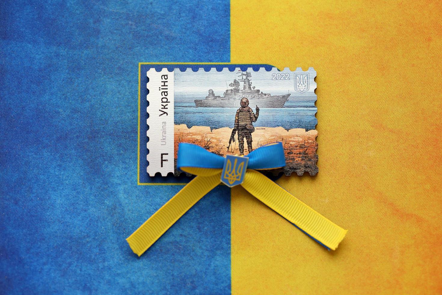 ternopil, Ucraina - settembre 2, 2022 famoso ucraino timbro postale con russo nave da guerra e ucraino soldato come di legno souvenir su nazionale bandiera foto