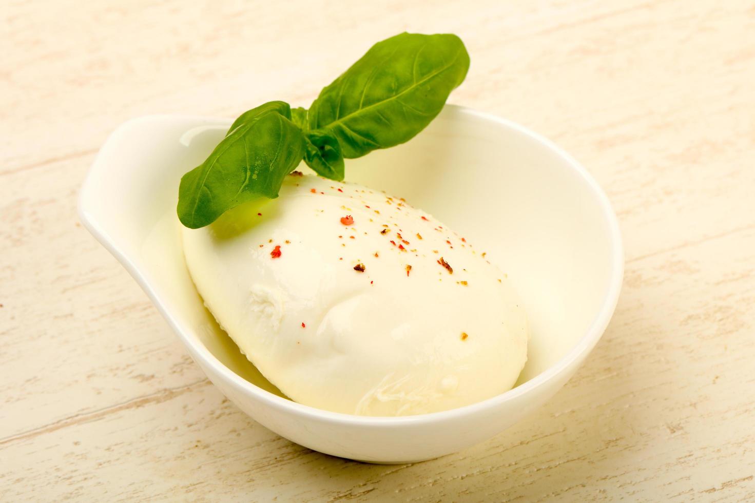 Mozzarella formaggio nel un' ciotola su di legno sfondo foto