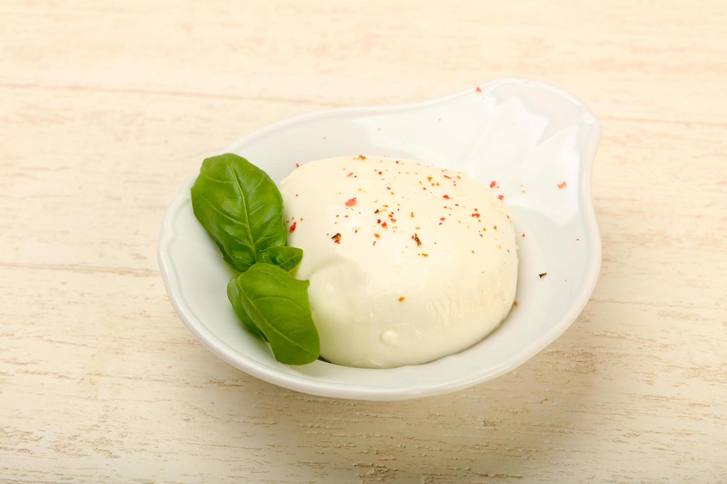 Mozzarella formaggio nel un' ciotola su di legno sfondo foto