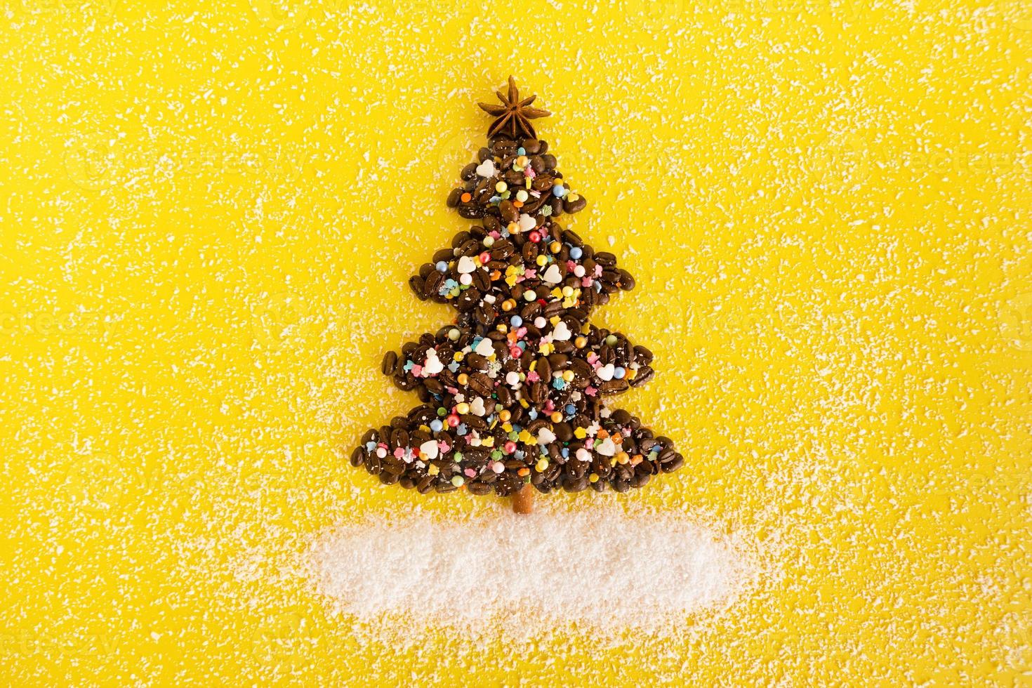 Natale albero fatto a partire dal caffè fagioli e decorato anice stella, multicolore culinario aspersione e Noce di cocco patatine fritte su un' giallo sfondo, superiore Visualizza. foto