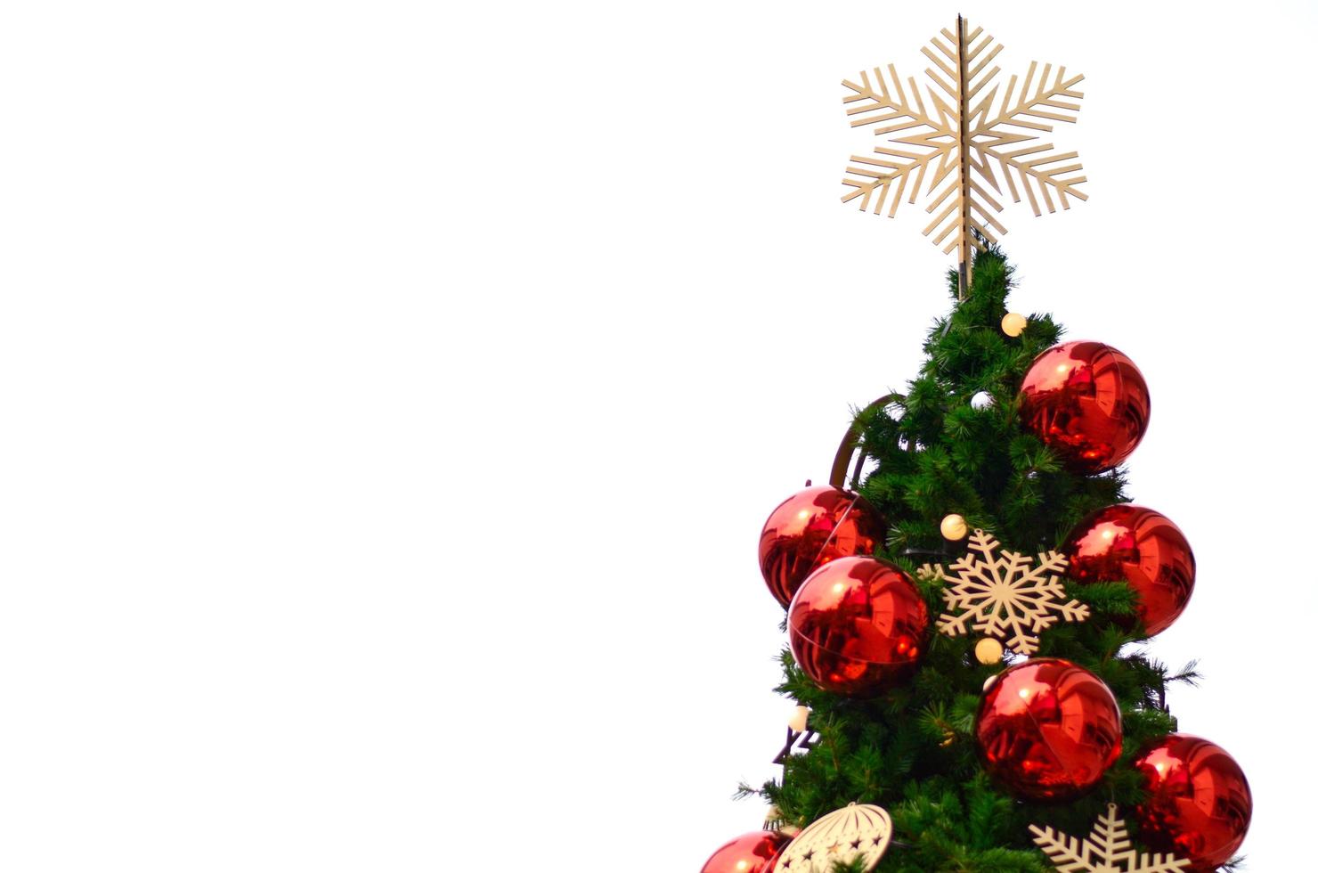 neve fiocco ornamento mette su il superiore di Natale albero con rosso palline e altro ornamenti isolato su bianca sfondo foto