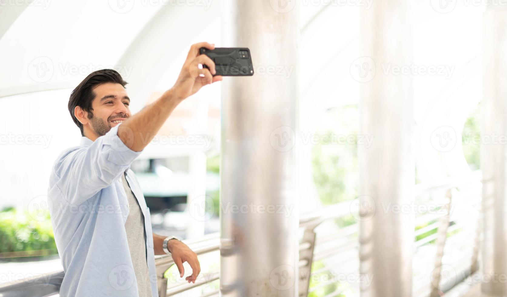 il giovane uomo autoscatto con lui stesso di il utilizzando smartphone per prendere foto, e aspettare per il suo amico. foto