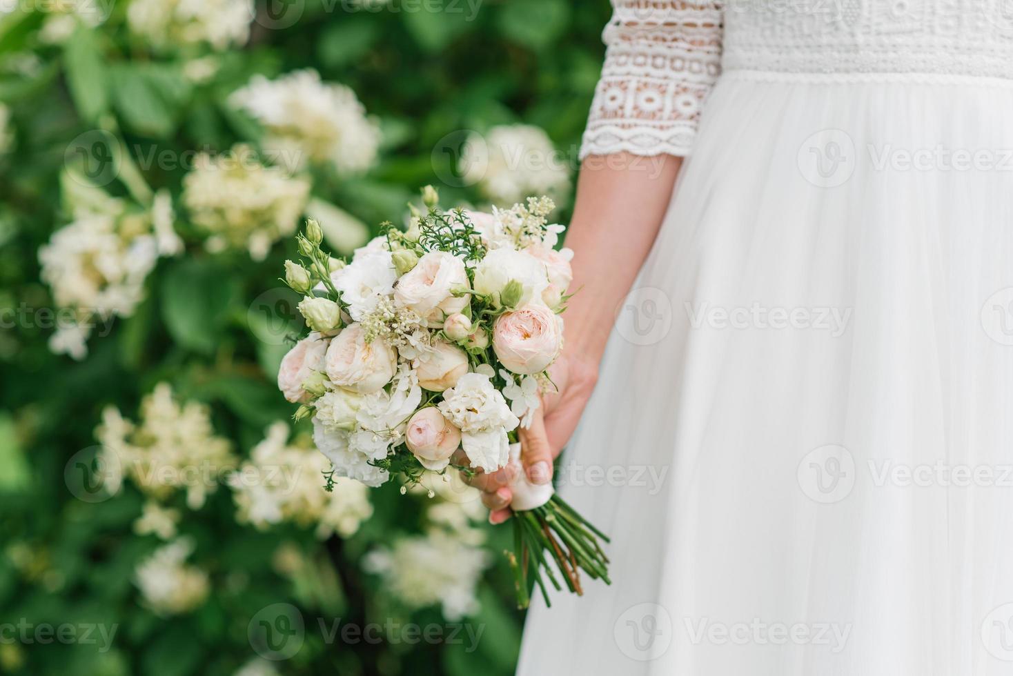 il sposa detiene nel sua mani un' bellissimo nozze mazzo di bianca e pesca fiori foto