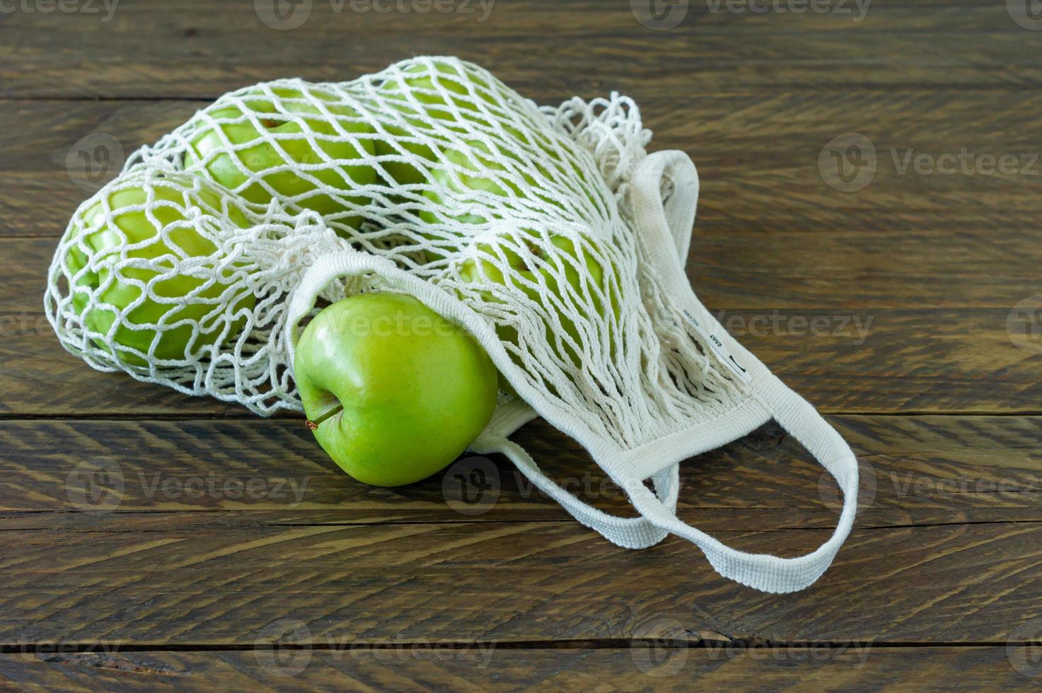 biologico nonna fabbro mele nel maglia tessile Borsa su di legno tavolo. foto