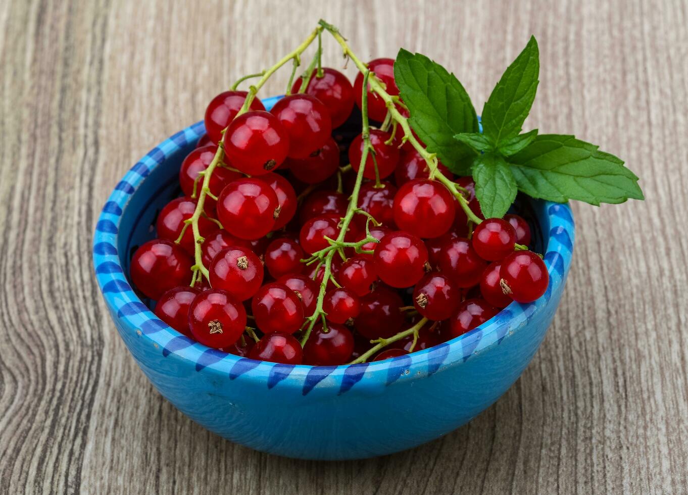 rosso ribes nel un' ciotola su di legno sfondo foto