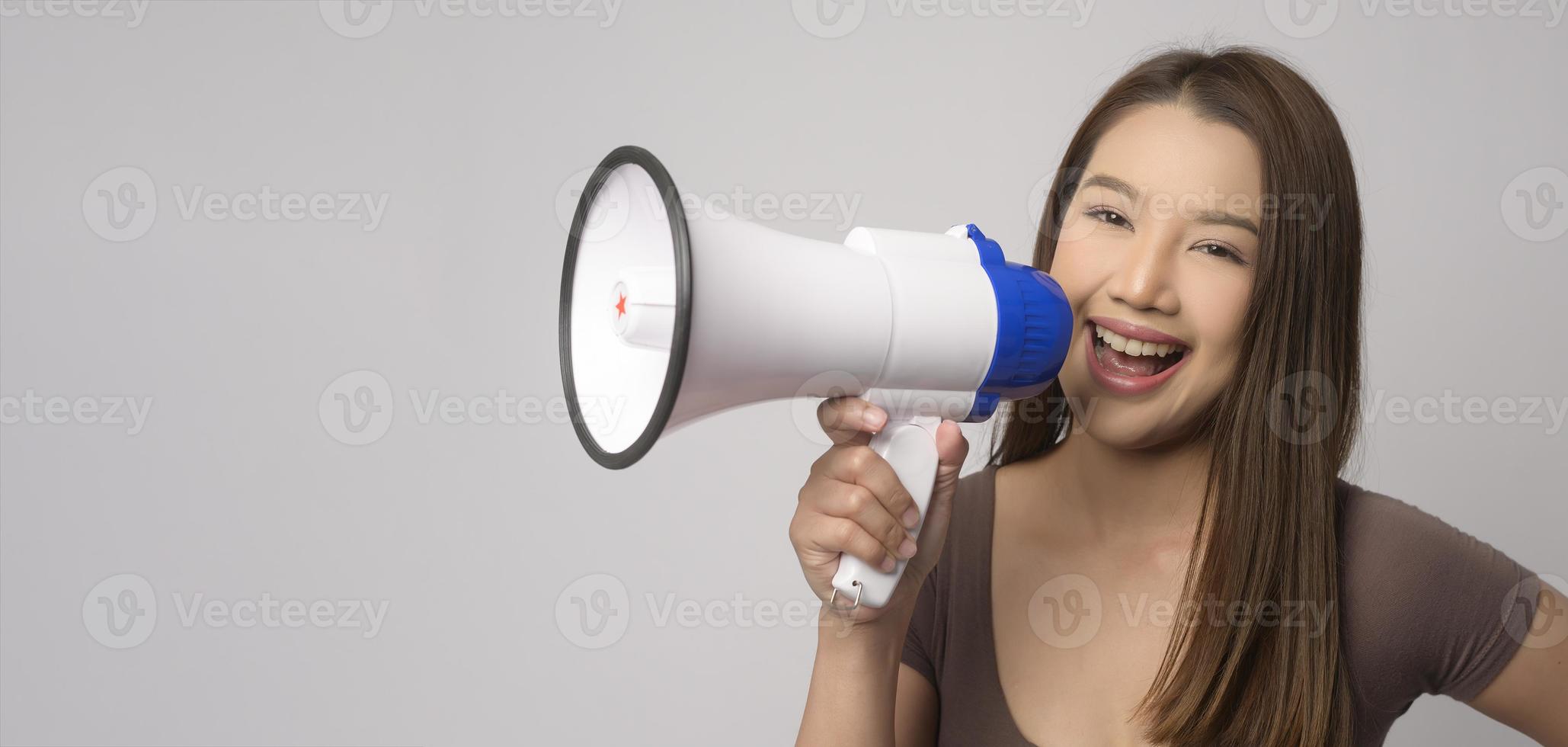giovane sorridente donna Tenere megafono al di sopra di bianca sfondo studio. foto