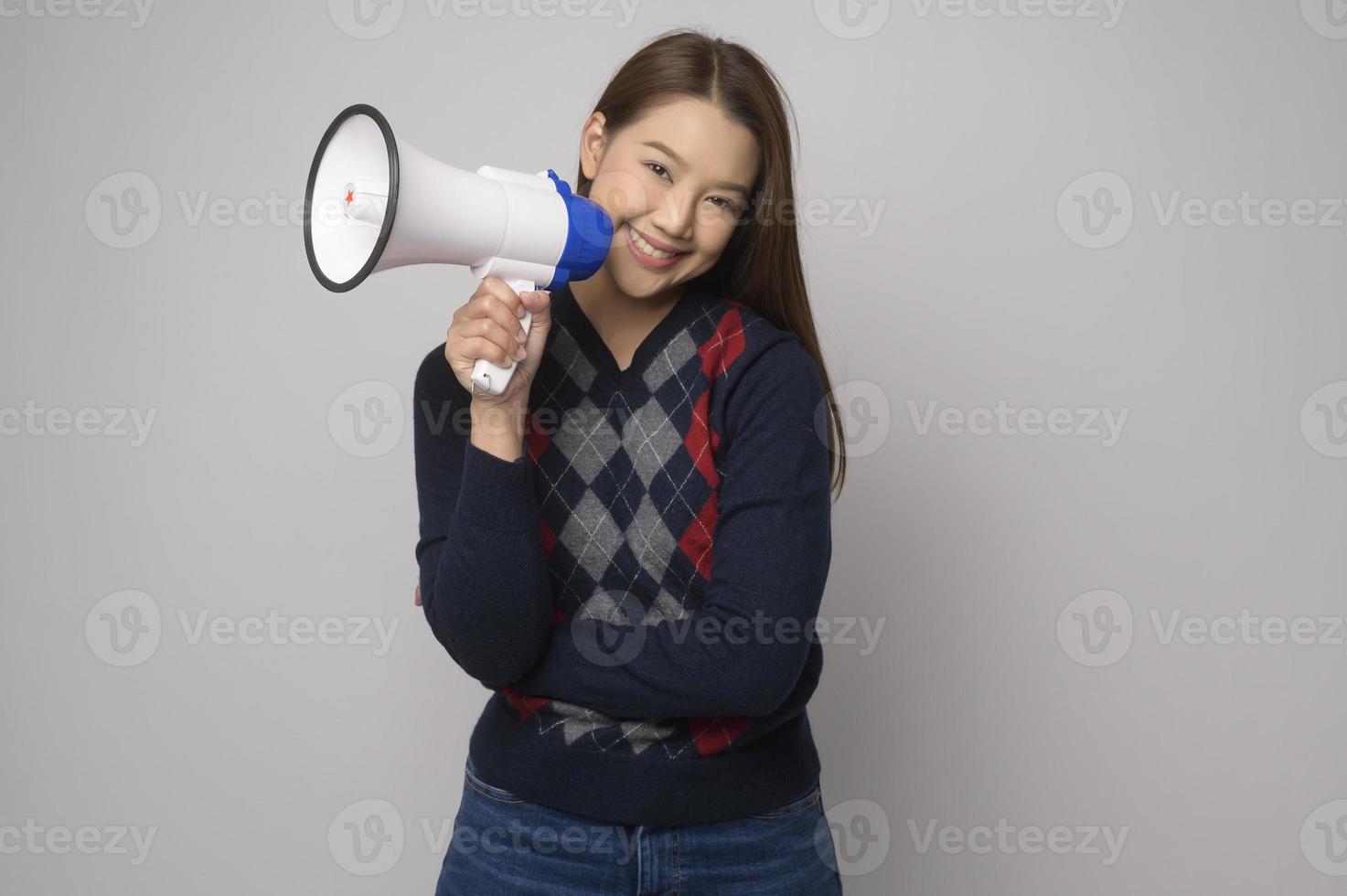 giovane sorridente donna Tenere megafono al di sopra di bianca sfondo studio. foto