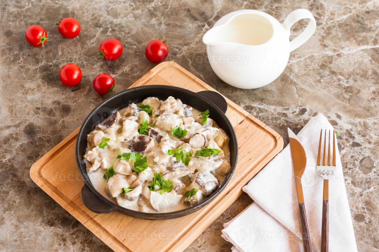 squisito piatto di bianca funghi nel acida crema con spezie nel un' frittura padella su un' marmo sfondo. foto