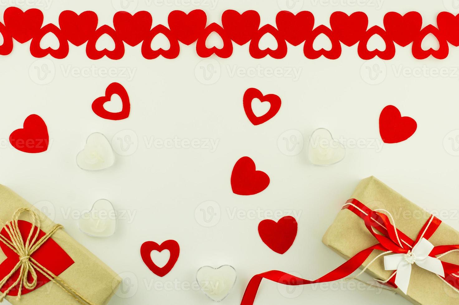 festivo sfondo per San Valentino giorno. arredamento di rosso cuori, candele nel il forma di un' cuore e regalo scatole nel mestiere carta. superiore Visualizza. piatto posizione. foto