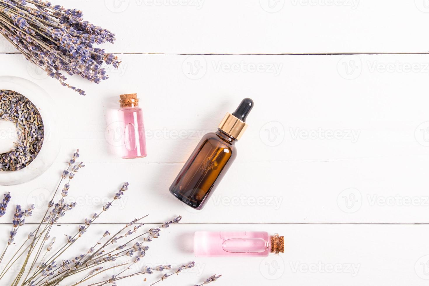 composizione di naturale cosmetico prodotti di fiori e semi di lavanda. siero o olio nel bicchiere bottiglie su un' bianca di legno sfondo. superiore Visualizza. foto